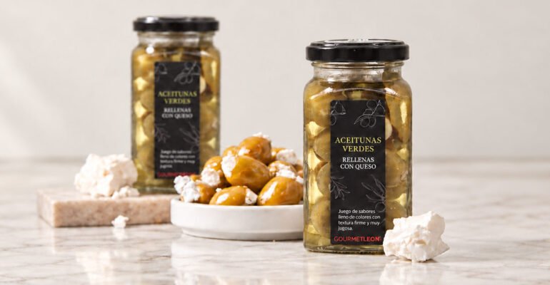Tarros de aceitunas rellenas de queso Gourmet Leon junto a un plato de aceitunas y queso