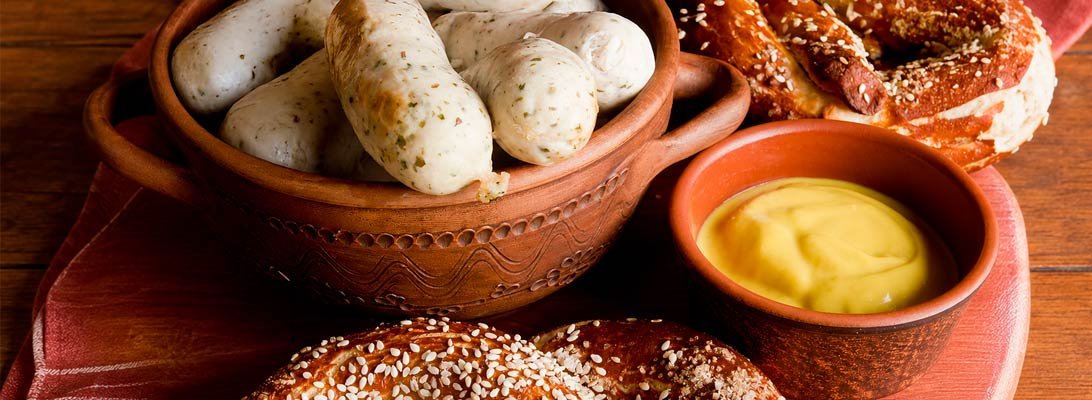 Salchichas y pretzels acompañados de mostaza de naranja y whisky Gourmet León, una combinación con matices cítricos, especiados y ligeramente ahumados. Salchichas y pretzels con mostaza de naranja y whisky
