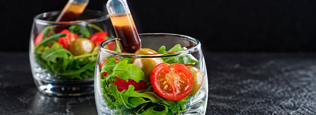 Vasitos de ensalada con hojas verdes tomates cherry aceitunas rellenas de queso y pipetas de alino Vasitos de ensalada con hojas verdes tomates cherry aceitunas rellenas de queso y pipetas de alino